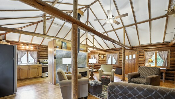 Un intérieur spacieux de chalet en bois, comprenant une cuisine, un coin repas et un espace salon.