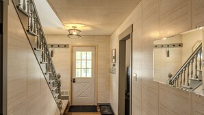 A hallway with a wooden floor, a door with a window, and a staircase with a railing. - Greenleaf-Summer in the U.P. • Minutes to Hancock Beach & Trails (Hancock)