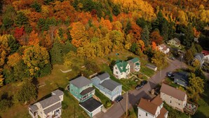 An aerial view of a residential area with houses surrounded by autumn-colored trees. - Greenleaf-Summer in the U.P. • Minutes to Hancock Beach & Trails (Hancock)