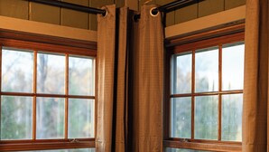 A room with two windows, each with a wooden frame and a view of a grassy area outside. - Craftsman Cottage: Your Perfect Summer Cottage — Swim, Paddle & Relax (Iron Mountain)