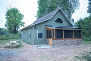A small, single-story house with a stone foundation and a sloped roof. - Craftsman Cottage: Cozy Fall Retreat — Peaceful Lake Cottage Surrounded by Color (Iron Mountain)