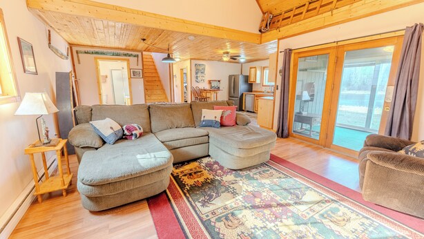 A cozy living room with a sectional sofa, a small table, and a patterned rug. - Craftsman Cottage: Your Perfect Summer Cottage — Swim, Paddle & Relax (Iron Mountain)