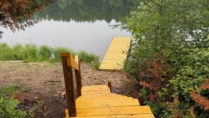 A wooden pathway leading to a body of water, surrounded by greenery. - Craftsman Cottage: Your Perfect Summer Cottage — Swim, Paddle & Relax (Iron Mountain)