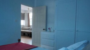 Een slaapkamer met een bed, een dressoir en een deur naar een andere kamer.