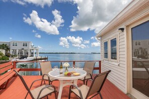 A deck with a table set for dining, overlooking a body of water with a distant shoreline.
