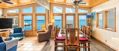 A spacious living area with a large dining table, comfortable seating, and a television.