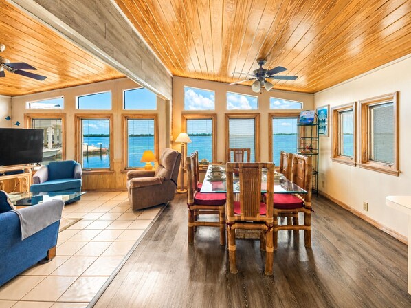 A spacious living area with a large dining table, comfortable seating, and a television.