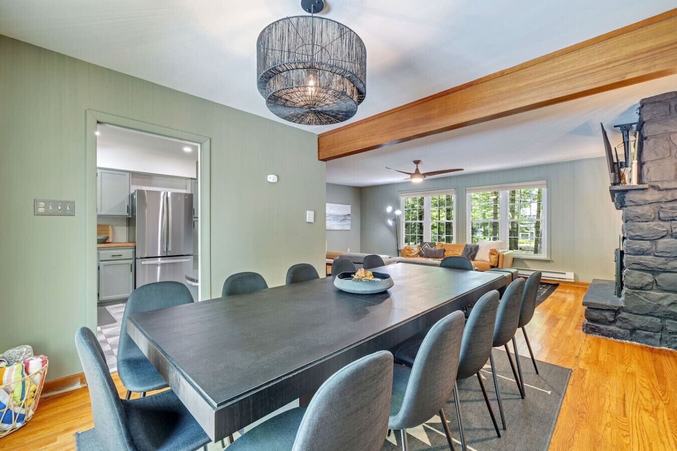 A spacious dining area with a long table, chairs, and a modern chandelier.