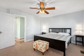 A bedroom with a bed, a nightstand, a lamp, a ceiling fan, and a door. - The Ranch: Updated Oceanside home in Duck, Close to Beach w/Views! (Duck)