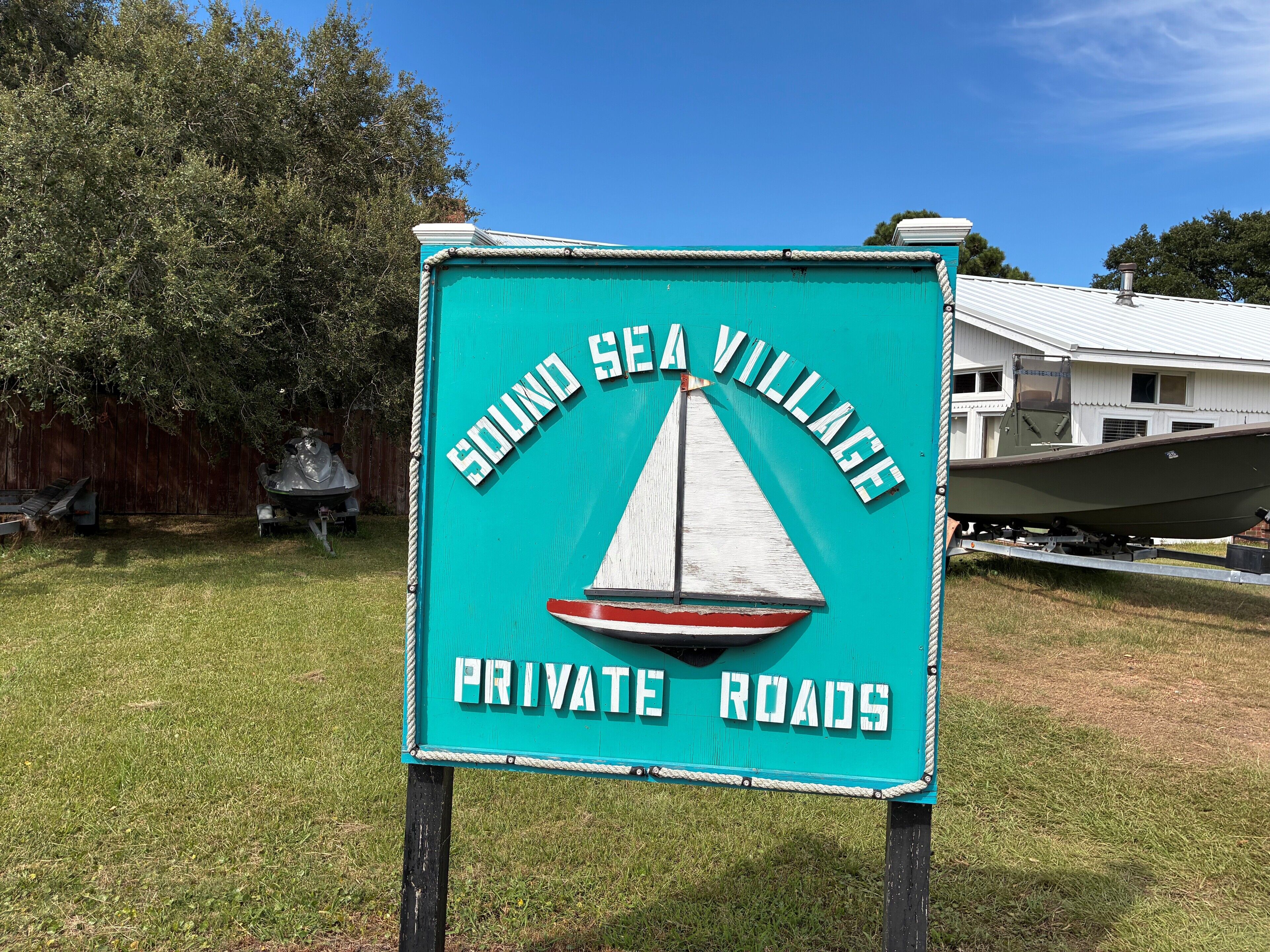 Señal de Sound Sea Village con un gráfico de velero e indicación de vías privadas.