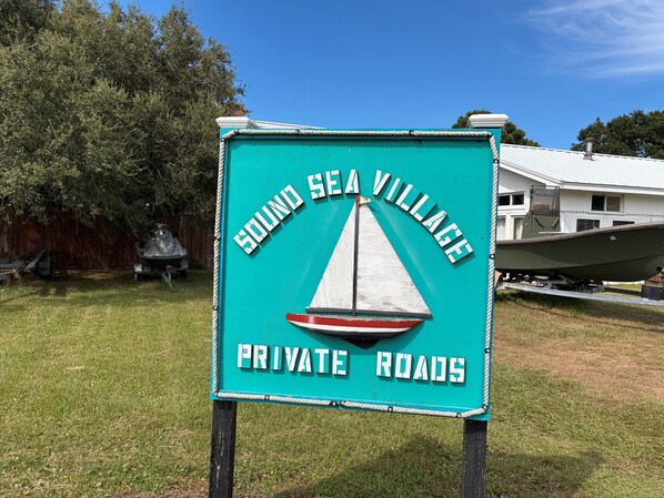 A sign for Sound Sea Village with a sailboat graphic and text indicating private roads.