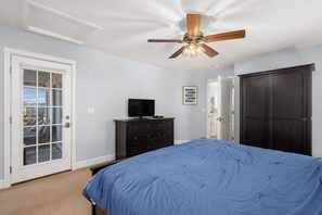 A bedroom with a bed, a ceiling fan, a dresser, and a door leading to a balcony. - The Ranch: Updated Oceanside home in Duck, Close to Beach w/Views! (Duck)