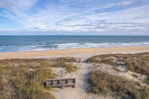 A beach with a wooden walkway leading to the shore, surrounded by dunes and vegetation. - The Ranch: Updated Oceanside home in Duck, Close to Beach w/Views! (Duck)