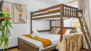 A bunk bed with a wooden frame, white bedding, and a yellow throw blanket. There is a plant on a shelf to the left and a ladder to the right.