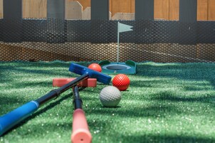 Pienoisgolfkenttä, jossa on vihreä keinonurmi, lippu ja golfpalloja.