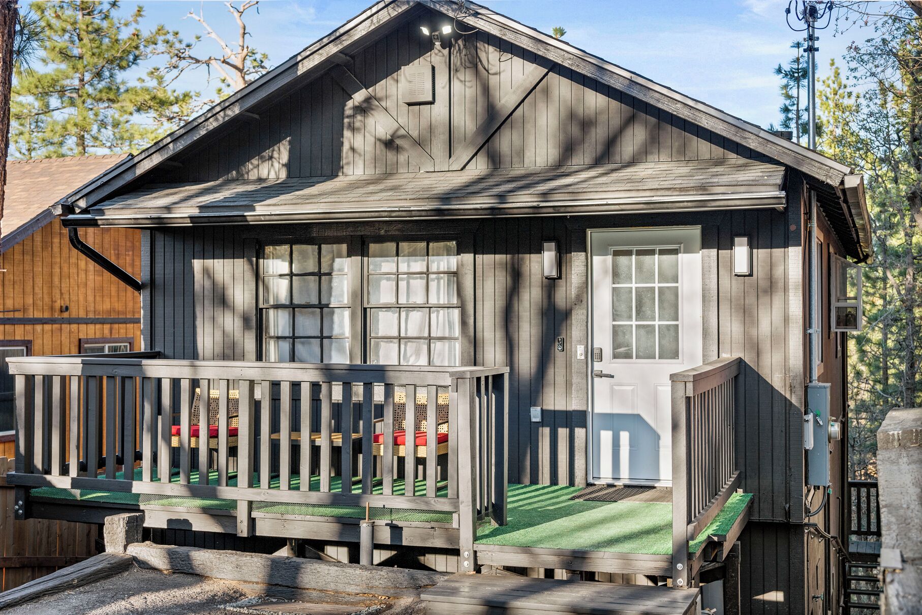 Een rustieke houten hut met een veranda, een deur en een klein raam.