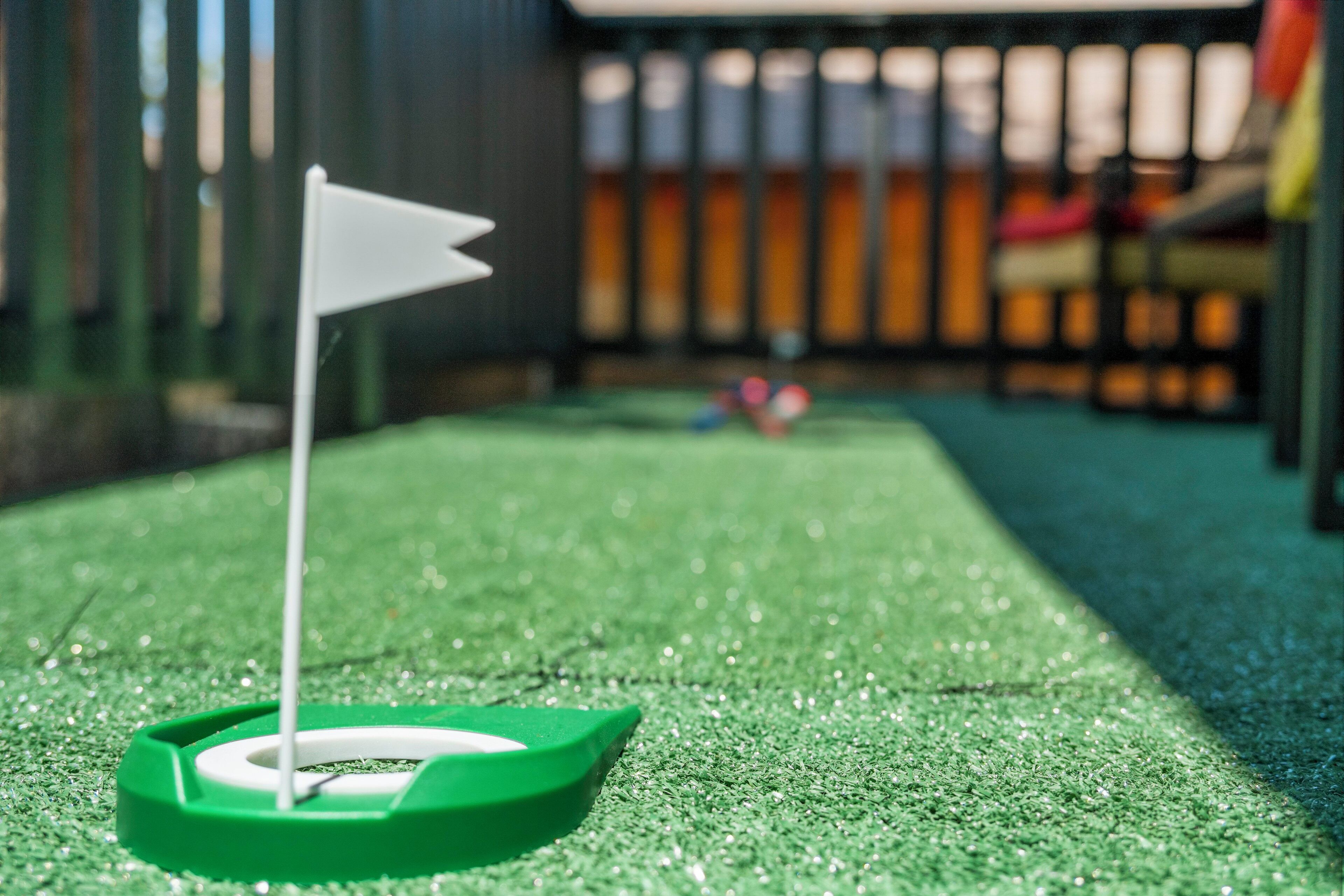 A miniature golf hole with a white flag on a green artificial turf.