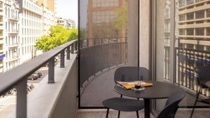 A balcony with a round table and two chairs, a mesh screen, and a view of city buildings. - 2-Bedrooms in Avenidas Novas with Balcony, Services and the Comfort of Home (Lisboa)