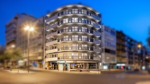 A multi-story hotel with a curved facade, balconies, and a ground-level shop. - 2-Bedrooms in Avenidas Novas with Balcony, Services and the Comfort of Home (Lisboa)