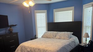A bedroom with a bed, a ceiling fan, a dresser, and a TV.