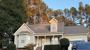 A single-story house with a front porch, a garage, and a driveway.