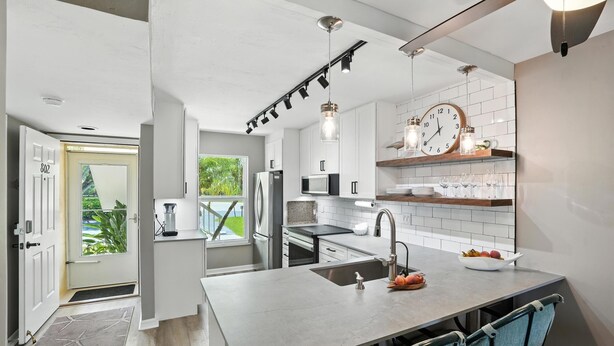 A modern kitchen with a large island, white cabinetry, and a view of the outdoors.