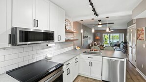 A modern kitchen with white cabinets, a stainless steel microwave, and a black induction cooktop.