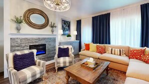Una sala de estar con chimenea, sofá, mesa de centro y televisor.