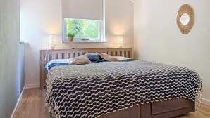 A bedroom with a bed, a window with a view of greenery, a wall-mounted mirror, and two bedside lamps. - Beautiful home in Hoeven with WiFi (Hoeven)