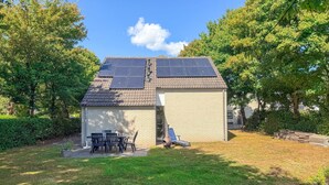 A house with a tiled roof, solar panels, a brick exterior, and a small patio with outdoor furniture. - Beautiful home in Hoeven with WiFi (Hoeven)