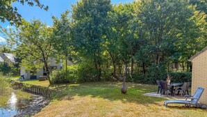 A backyard with a pond, a patio with chairs, and a building with a brick exterior. - Beautiful home in Hoeven with WiFi (Hoeven)