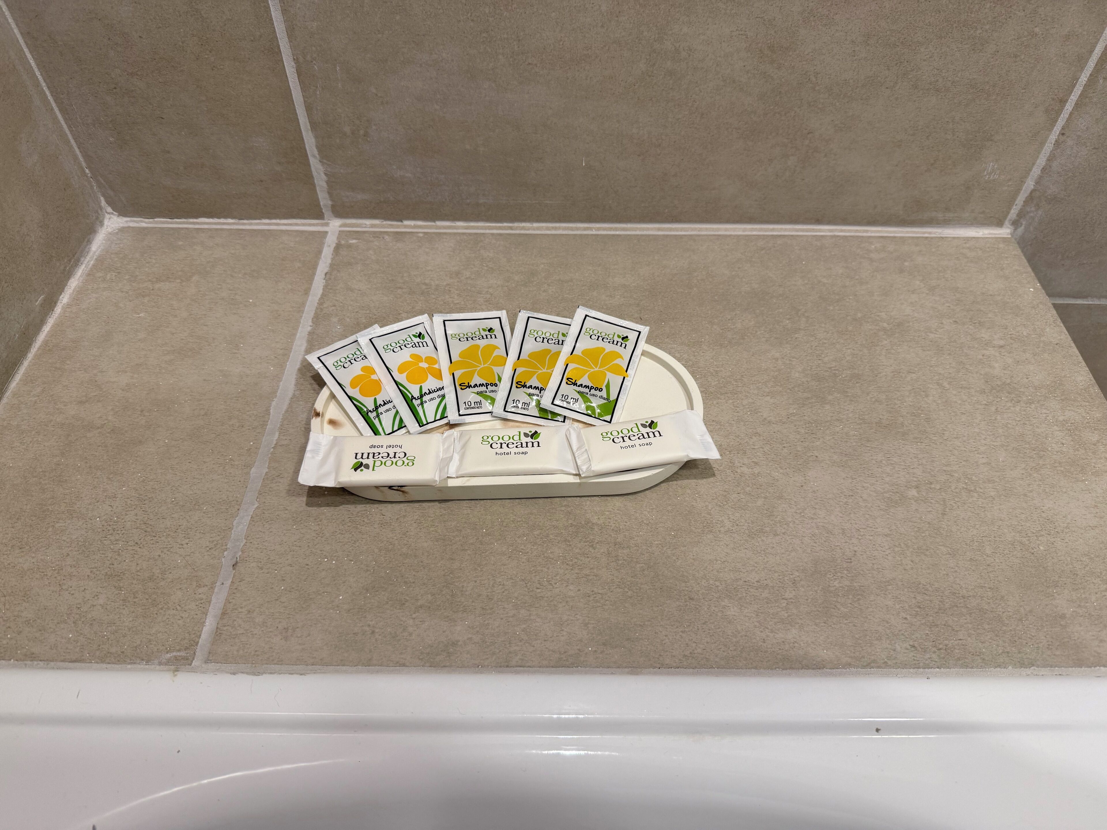 Une salle de bain avec une baignoire, un lavabo blanc et une étagère contenant des articles de toilette, notamment du shampoing et du savon.