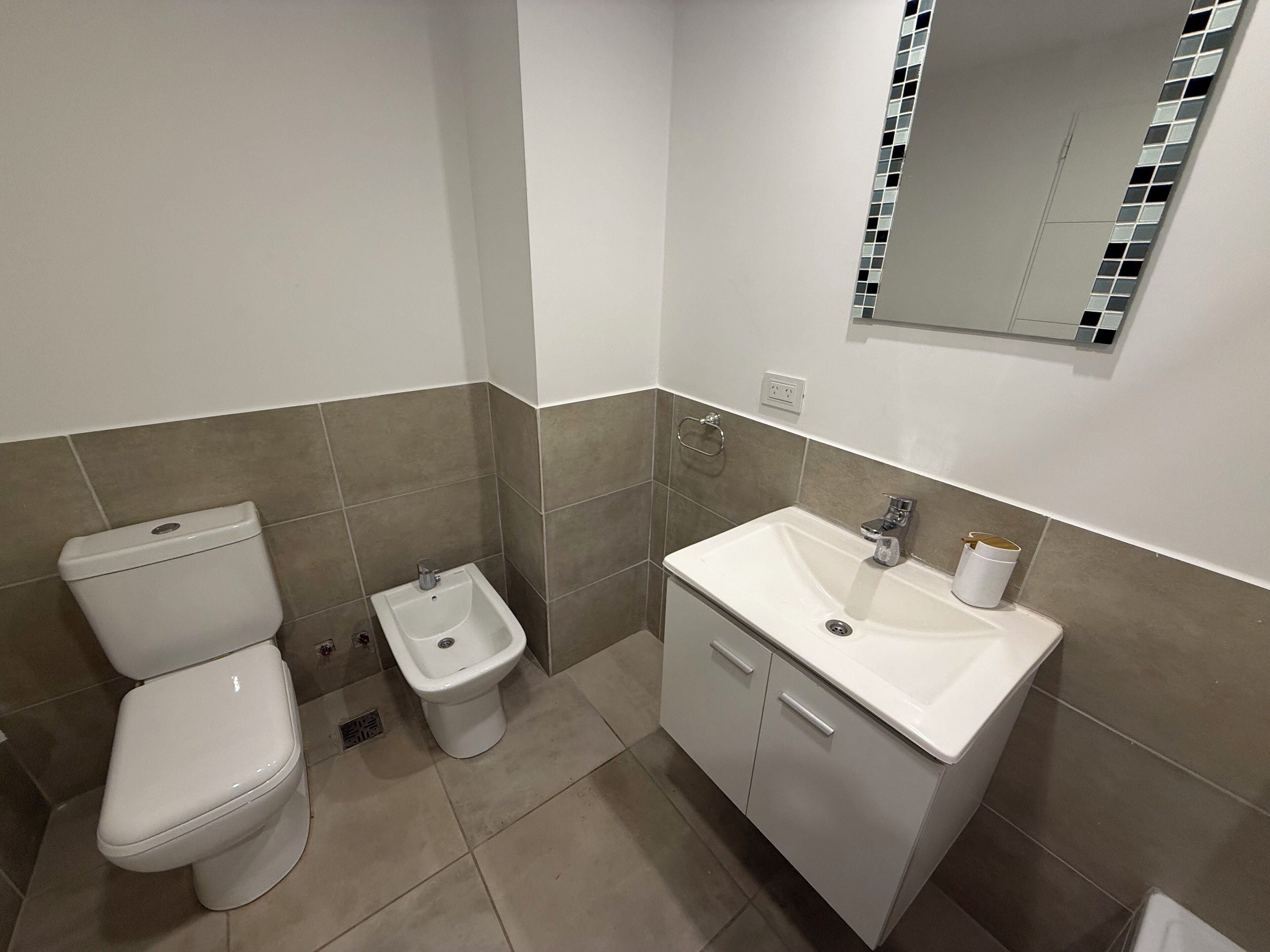 Un bagno moderno con WC, bidet e lavandino.
