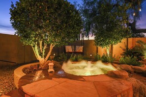 A landscaped garden with a water feature, trees, and a brick wall.