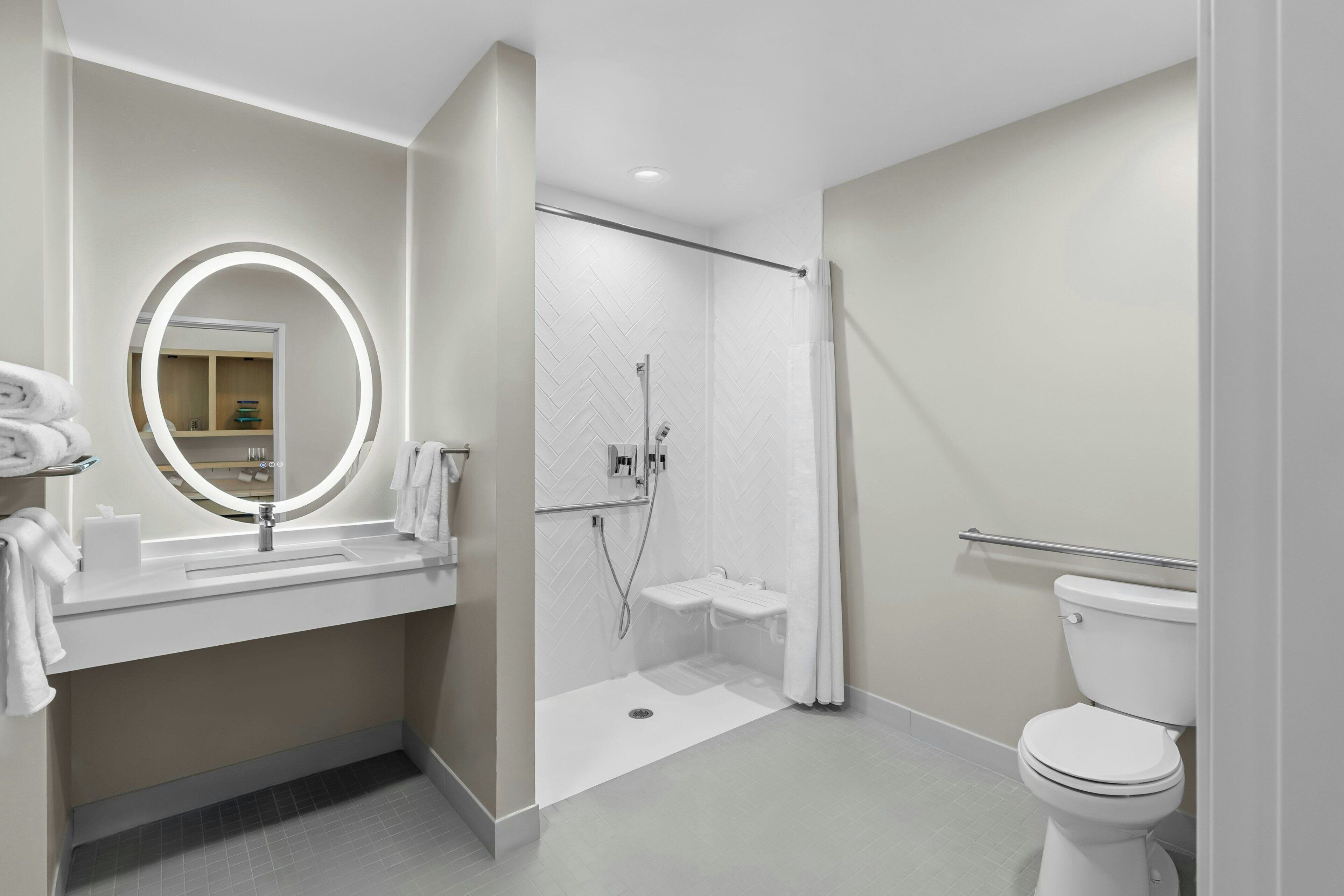 A modern bathroom with a sink, mirror, shower, and toilet.