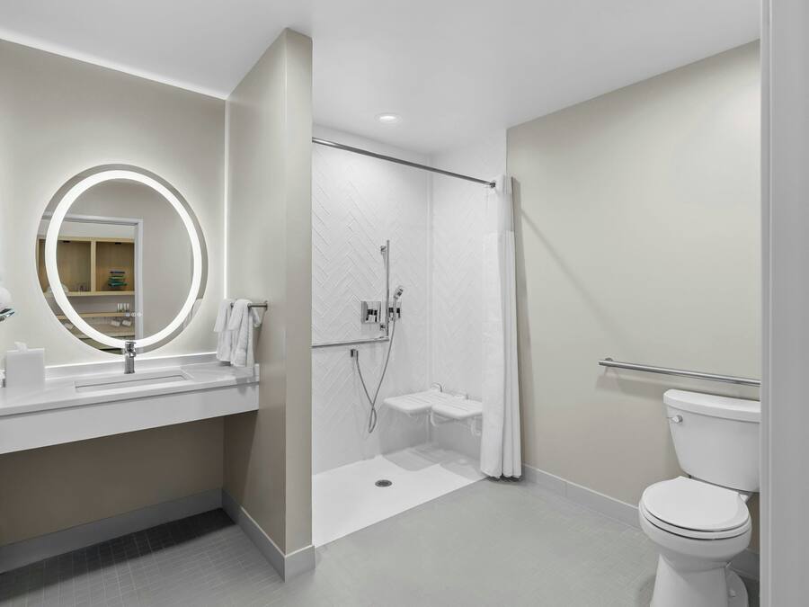 A modern bathroom with a sink, mirror, shower, and toilet.