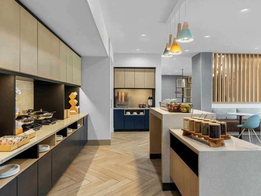 A modern kitchen with a central island, wooden cabinets, and pendant lighting.
