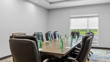 A conference room with a long table, multiple chairs, and green bottles.