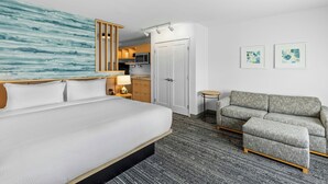 A hotel room with a bed, a sofa, a small table, a microwave, a cabinet, and artwork on the wall. - Towneplace Suites By Marriott Youngstown North (Girard)