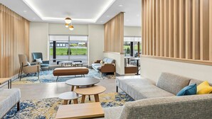 A modern hotel lobby with seating areas, a large window offering a view, and a ceiling with recessed lighting. - Towneplace Suites By Marriott Youngstown North (Girard)