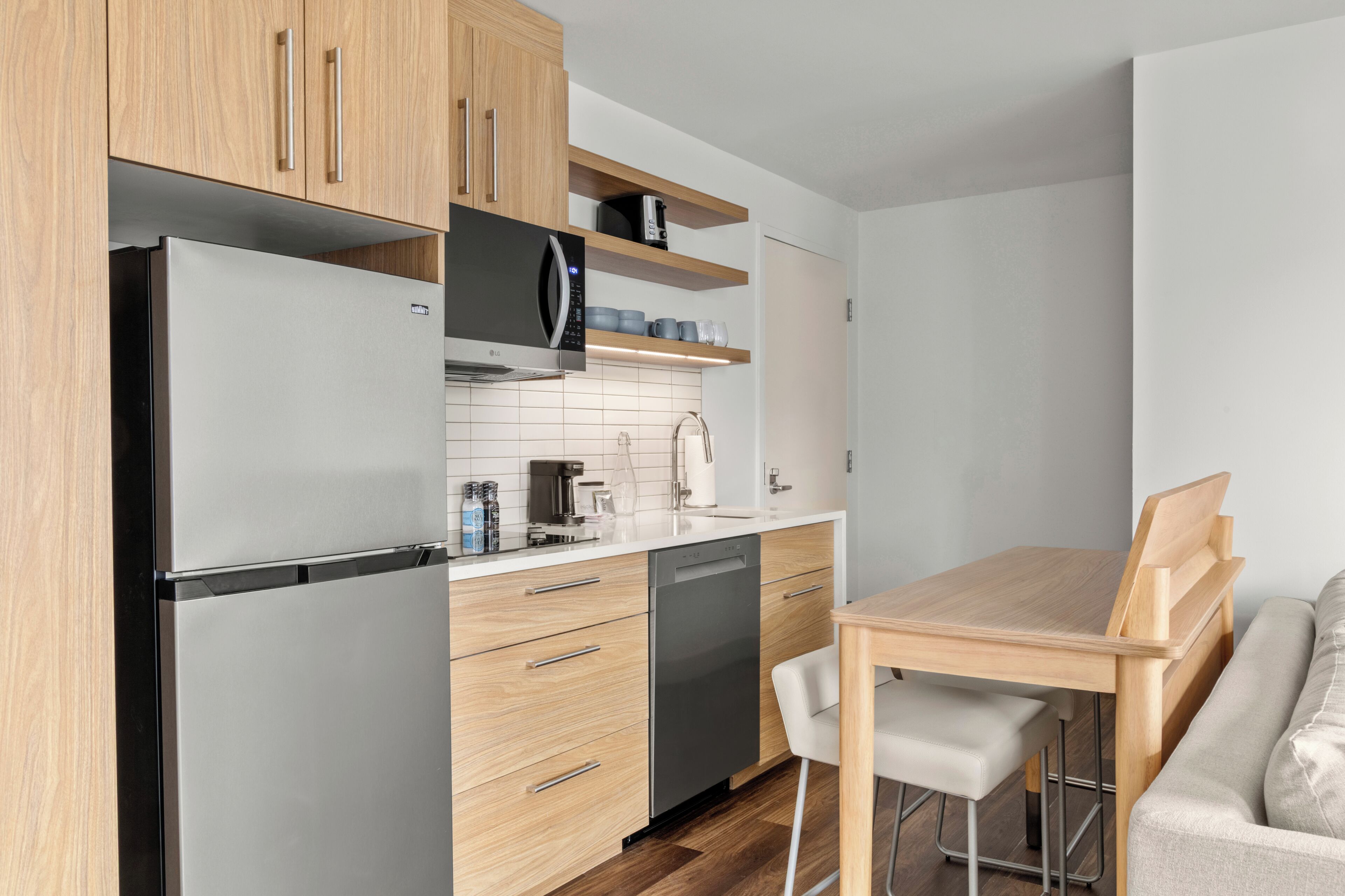 Cuina moderna amb nevera d'acer inoxidable, armaris de fusta, forn de microones integrat i rentavaixelles.