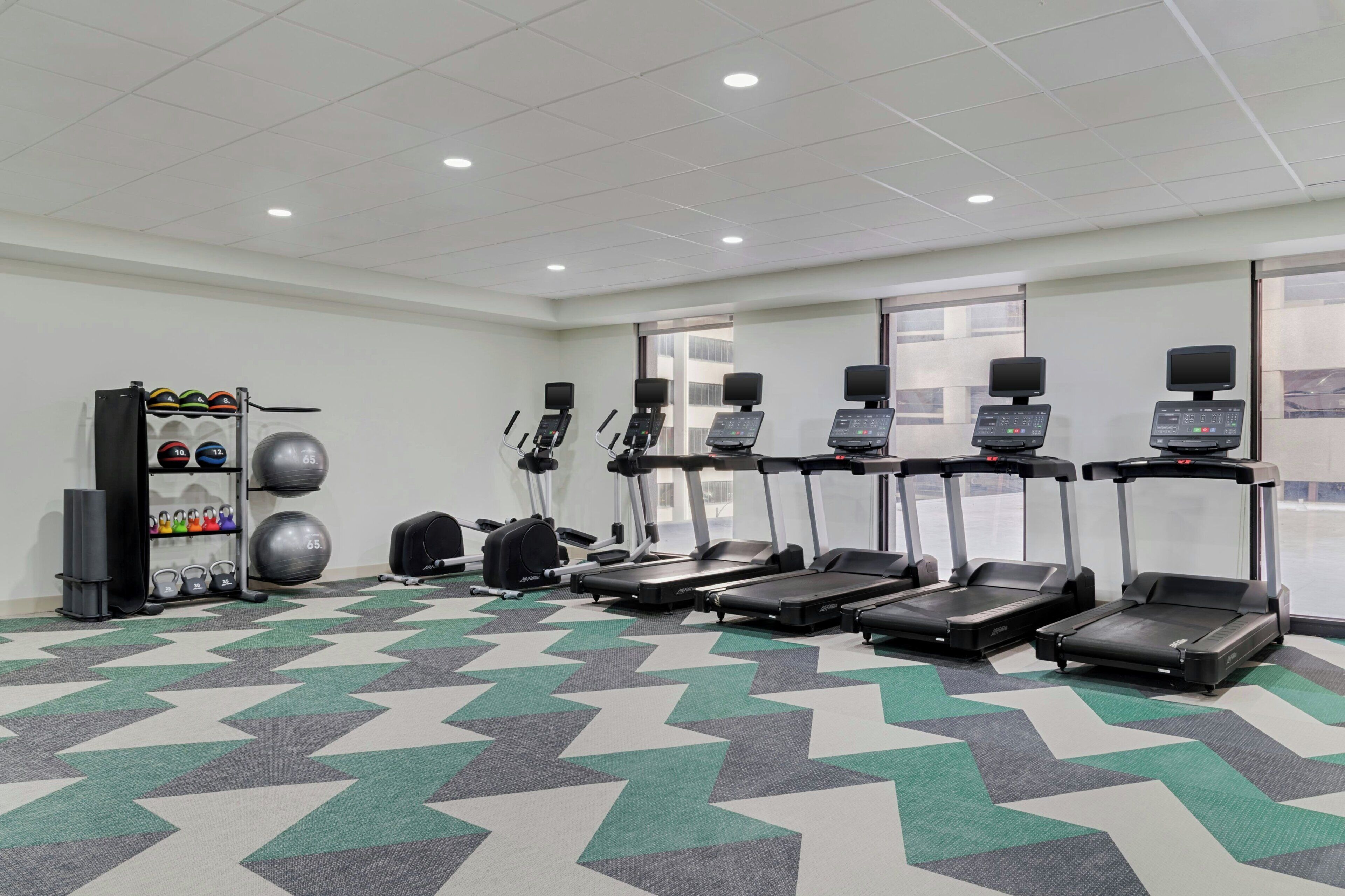 A gym with treadmills, exercise balls, and a weight rack.