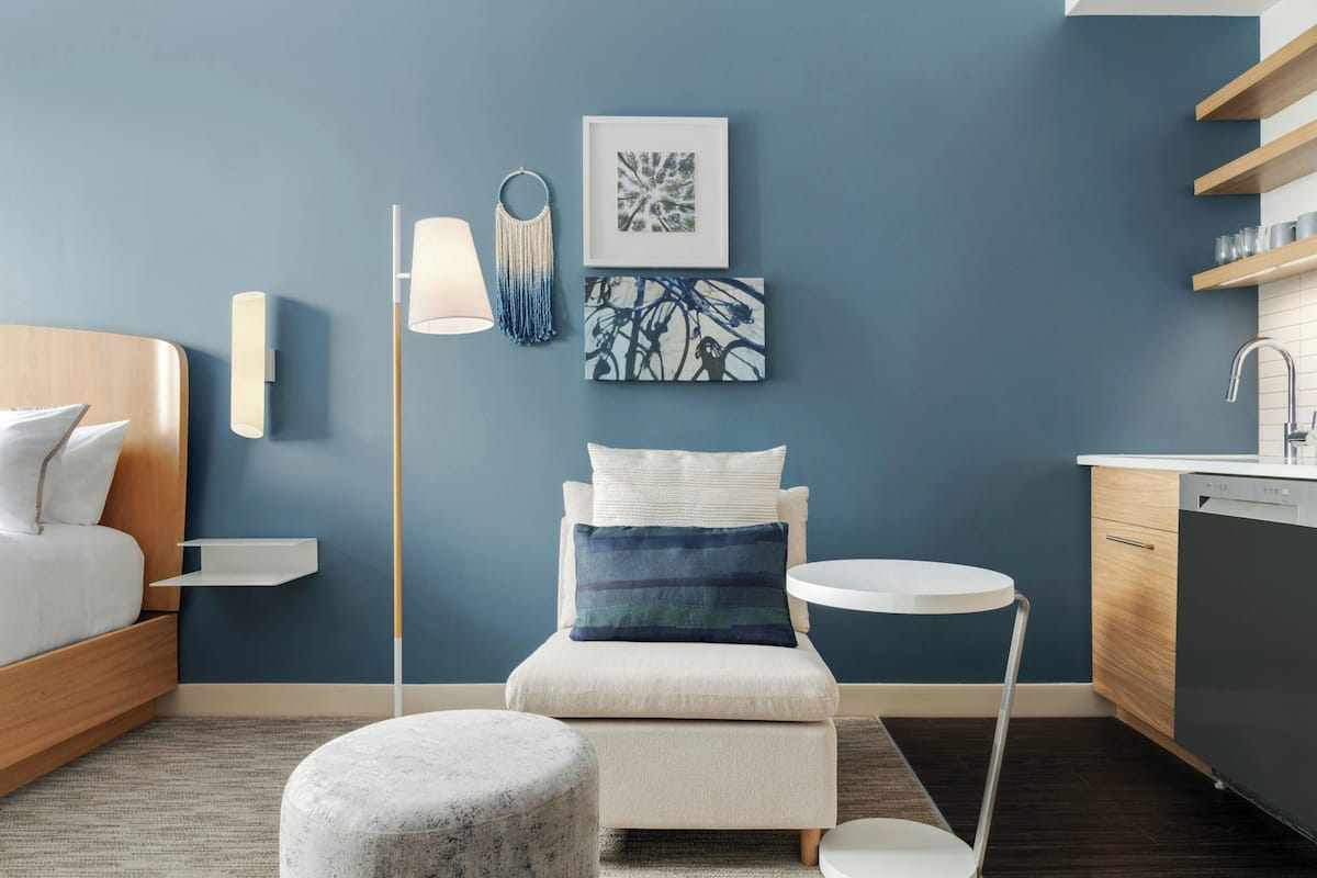 A modern bedroom with a bed, bedside table, lamp, and artwork on the wall.