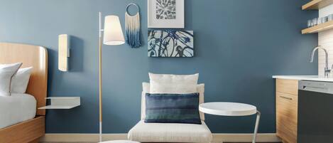 A modern bedroom with a bed, bedside table, lamp, and artwork on the wall.