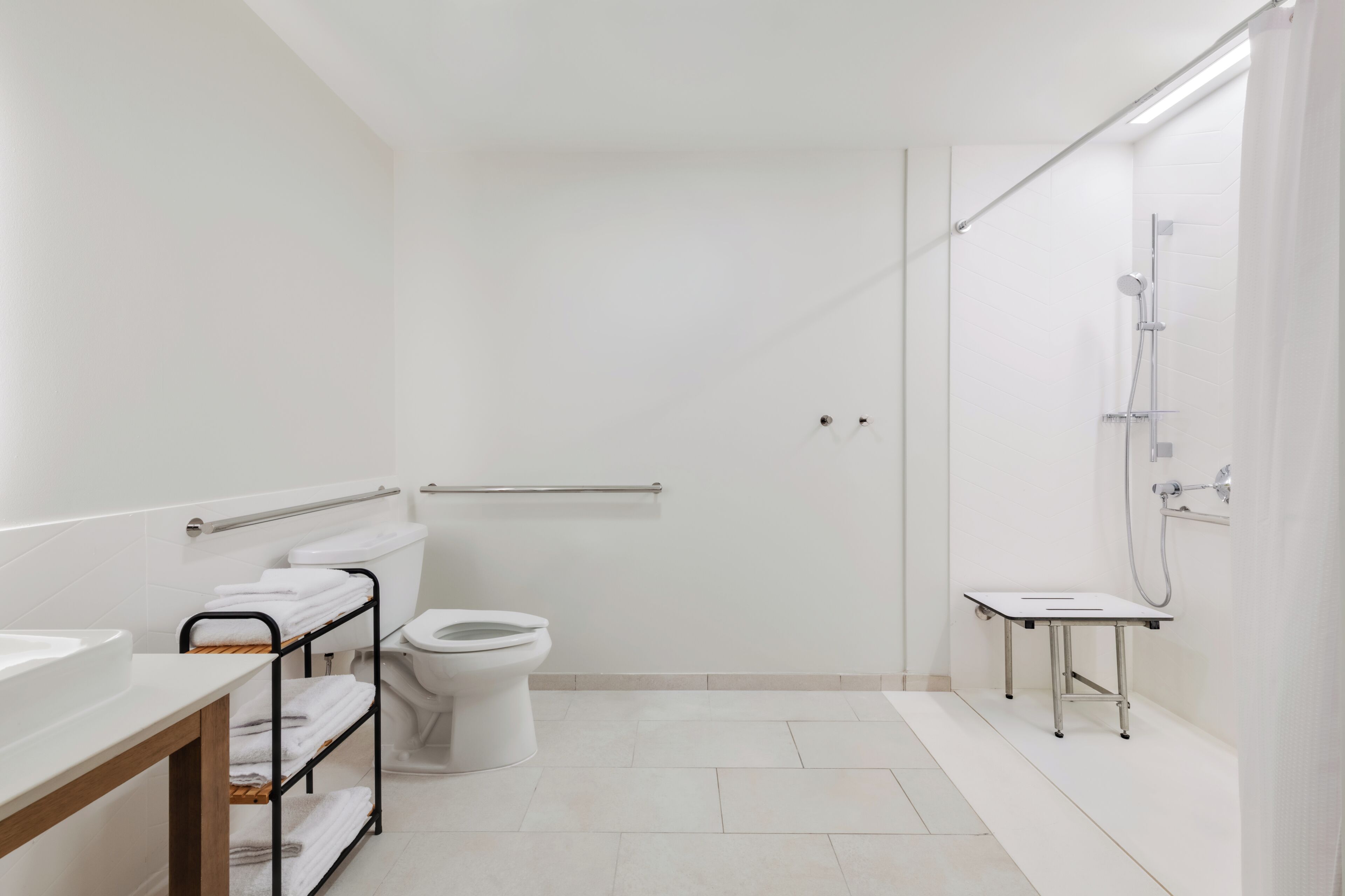 A modern bathroom with a toilet, a sink, a shower, and a towel rack.