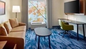 A hotel room with a sofa, a small table, a desk with a chair, a flat-screen TV, and a large window with curtains. - Fairfield By Marriott Inn & Suites Savannah Pooler (Pooler)