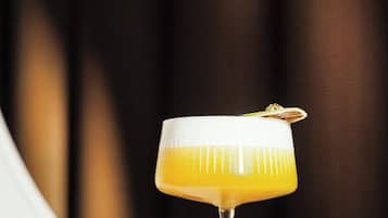 A cocktail in a stemmed glass with a garnish on a wooden surface.
