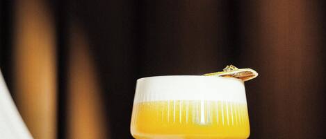 A cocktail in a stemmed glass with a garnish on a wooden surface.