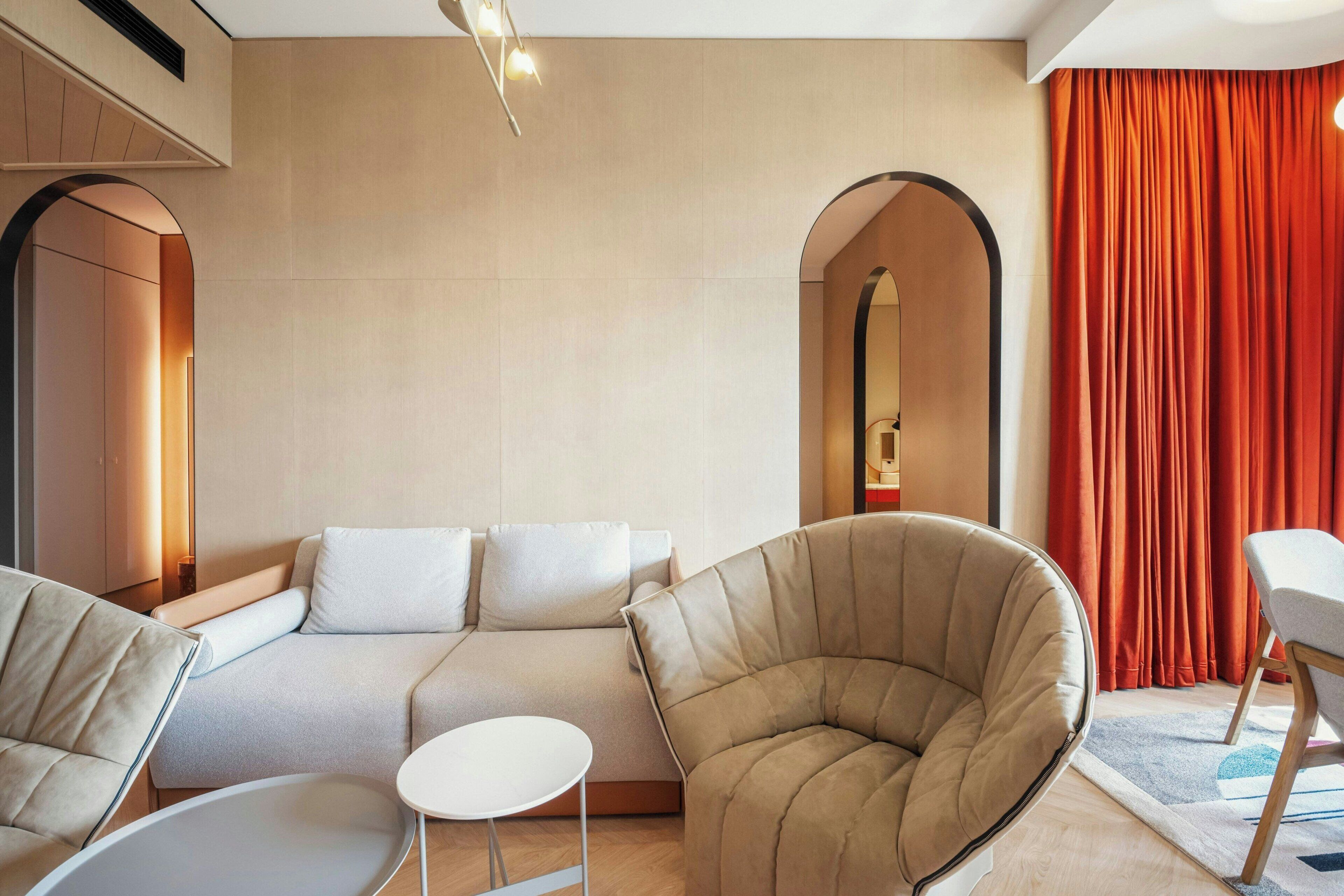 A modern living room with a sofa, armchairs, and a small table.