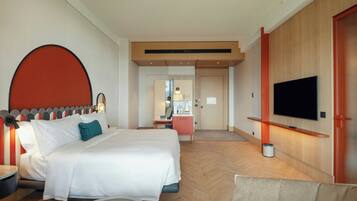 A hotel room with a bed, a TV, a desk, and a bathroom visible in the background.